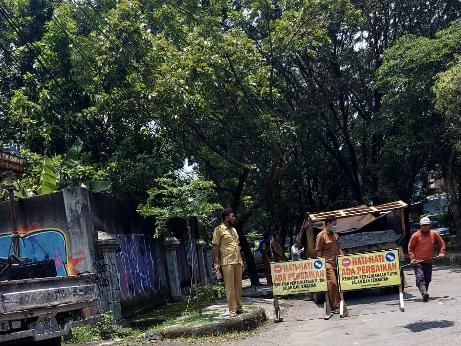 TAMBAL SULAM: Petugas Dinas Pekerjaan Umum dan Tata Ruang atau DPUTR Kota Cirebon menambal-sulam jalan yang berlubang di Jalan Terusan Pemuda, atau dekat Kantor Dinas PUTR. --FOTO: ABDUL HAMID/RADAR CIREBON