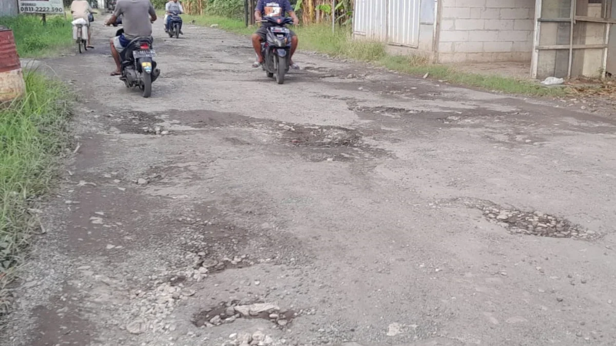 Pengendara sepeda motor menghindari jalan berlubang di Blok Kalijaga Mundu Pesisir.