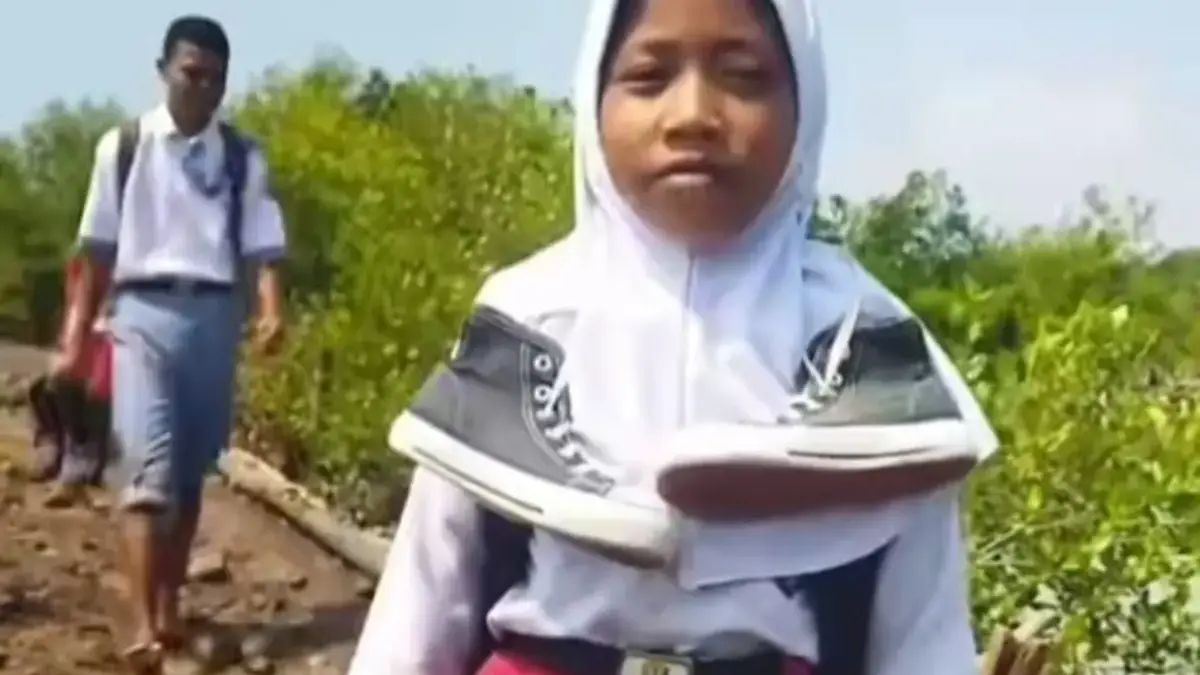 pelajar lintasi jalan rusak tanpa alas kaki